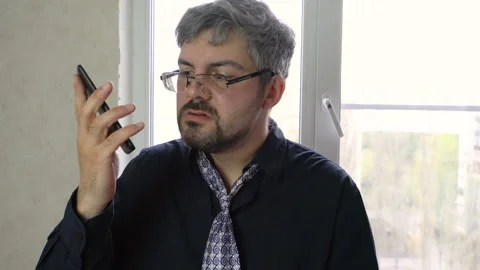 Drunk man in glasses with a beard talking on a smartphone 4K Stock Footage 129529513