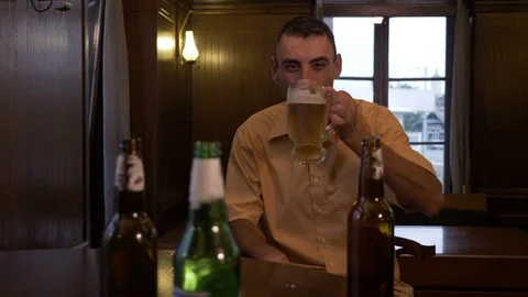Drunk man laughing and drinking beer alone at a pub Stock Footage 81721968