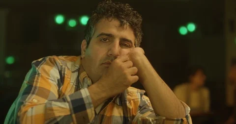 Drunk man leans on his elbow on a bar counter and looks sadly into the Stock Footage 120747506
