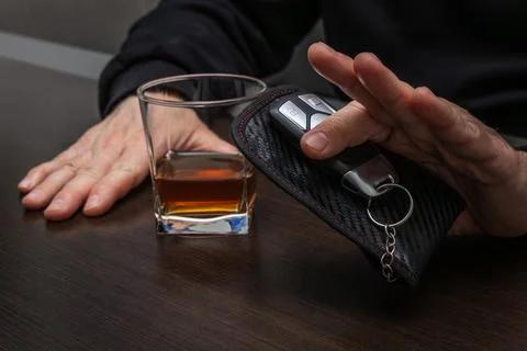 Drunk man lying on the table with a glass of alcohol, car keys on the count.. Stock Photos