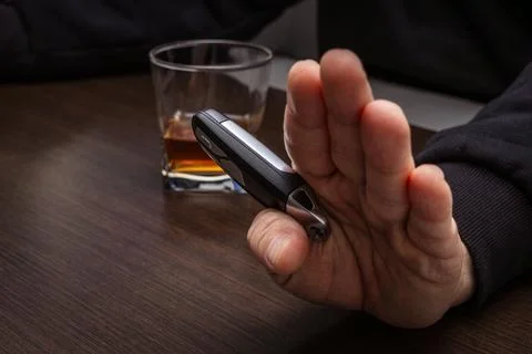 Drunk man lying on the table with a glass of alcohol, car keys on the count.. Stock Photos