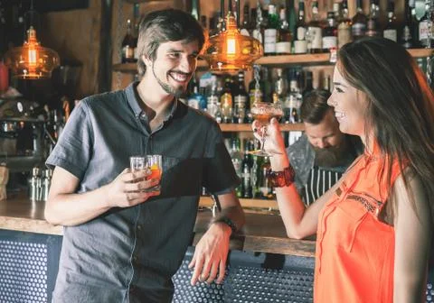 Drunk man sitting at bar, drinking cocktail, looking at girls Stock Photos