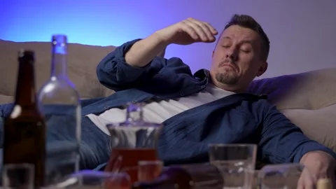 Drunk man sleeping on a sofa after celebrating party at home Stock Footage 266150034