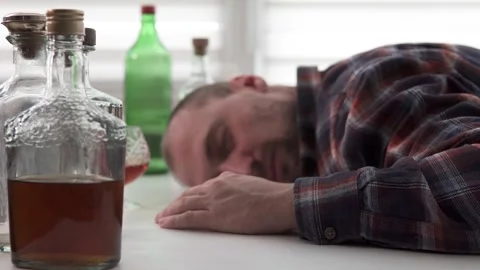 A drunk man sleeps at the table. Alcohol addiction concept. Stock Footage 257399365