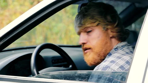 A drunk man with a yellow beard sits in an old car Stock Footage 229558859