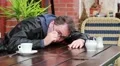 Drunk, overworked, sick or tired man wakes up in outdoor cafe HD Footage
