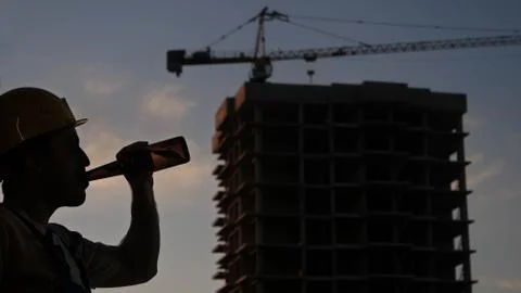 Drunk worker in yellow helmet at construction site. Stock Photos