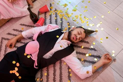 Drunk young man with bra sleeping on carpet after party in bedroom, top view Stock Photos