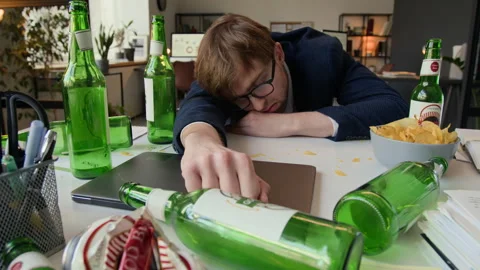 Drunk Young Man Passing Out at Office Desk, Surrounded by Empty Beer Bottles Stock Footage 331530684
