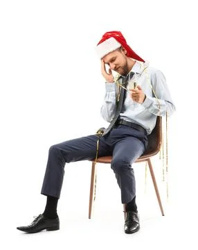 Drunk young man with Santa hat and champagne sitting in chair after Christmas Stock Photos