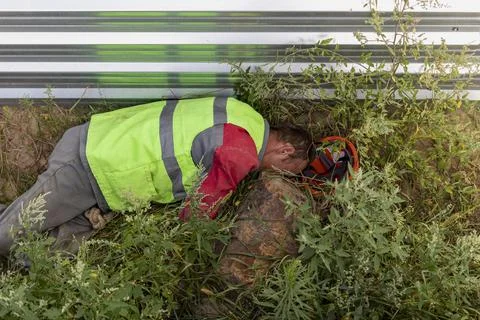 A drunken construction worker sleeps in the grass near Stock Photos