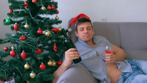 Drunken guy in red cap nerd drinking wine from bottle at Christmas holidays. Video stock 136055946