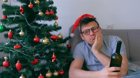 Drunken guy in red cap nerd drinking wine from bottle at Christmas holidays. Video stock 137781790