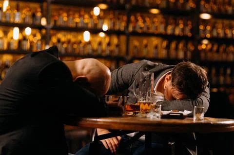 Drunken men sleeping on a table in a pub after work. friends, drink alcohol Foto stock