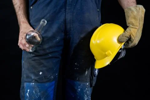 Drunkenness at work. Protective accessories and an empty bottle kept by an em Stock Photos