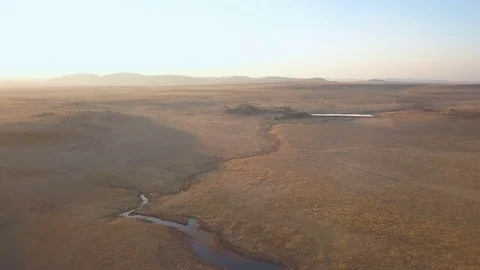 Dry African countyside at sunset with small river flying over settlement Video stock 79806829