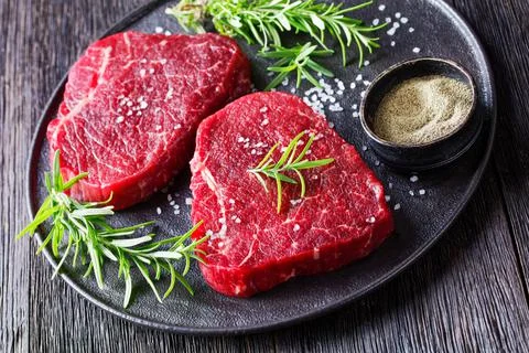 Dry-aged beef steaks on a black plate Stock Photos
