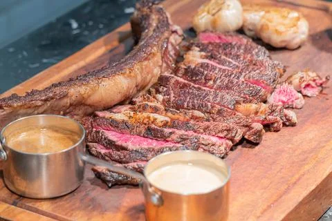 Dry-aged marble beef steak Tomahawk on wooden board with spices. Close-up, di Stock Photos