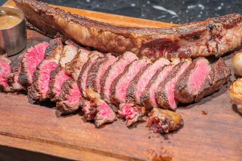 Dry-aged marble beef steak Tomahawk on wooden board with spices. Close-up, di Stock Photos