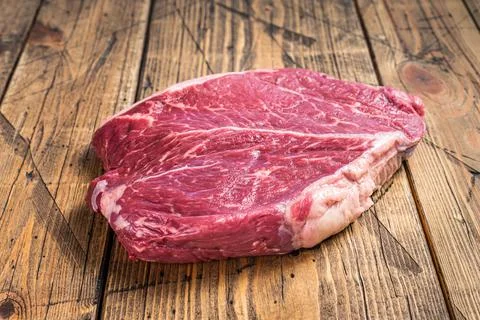 Dry aged raw beef round steak cut on a butcher table. wooden background. Top Stock Photos