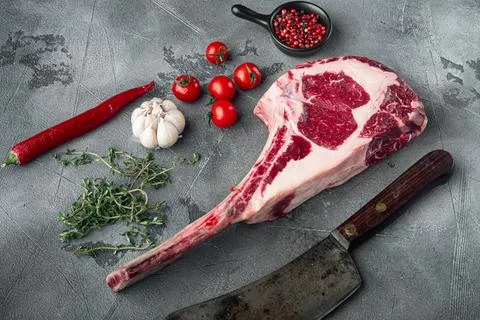 Dry aged raw tomahawk beef steak with ingredients for grilling, and old butch Stock Photos