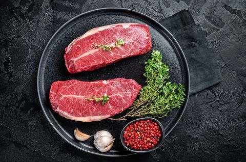 Dry aged Raw top blade flat Iron beef meat steaks. Black background. Top View Stock Photos