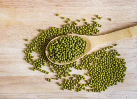 Dry and uncooked mung beans in spoon on wooden background Stock Photos