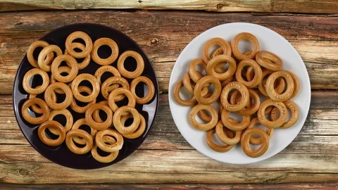 Dry bagels on the plate. Two plates on the surface of a wooden table. Rough w Video stock 101347615