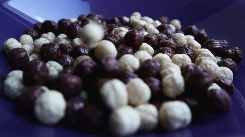 Dry balls of cereal in slow motion poured into a blue plate close-up Stock Footage 127529305
