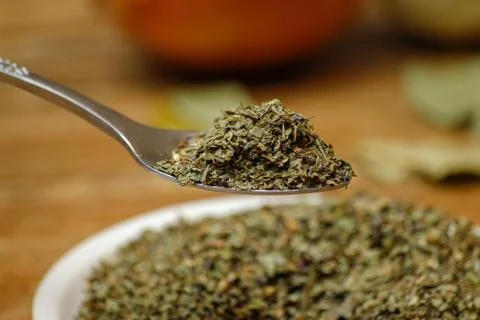 Dry basil spice in metal spoon and ceramic plate Stock Photos