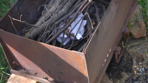 Dry branches in Iron fire brazier. Man making bonfire before cooking barbeque Stock Footage 247469622