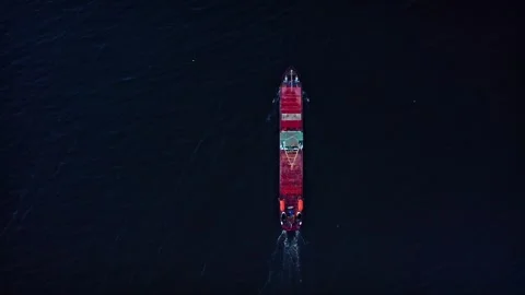 A dry cargo ship sailing at night, red deck and orange life boats on board. Top Stock Footage 257764535