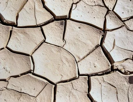 Dry clay surface with natural cracks forming abstract geometric texture patte Stock Photos