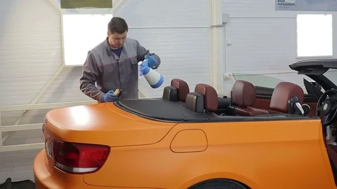 Dry cleaning of a cabriolet .Master cleans the rear of the body.Two shot Stock Footage 76356370