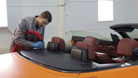 Dry cleaning of a cabriolet .Master cleans the rear of the body.Two shot Stock Footage 76357094