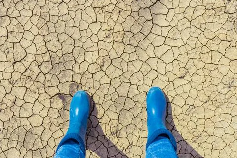 Dry cracked land surface texture with farmer boots from above Stock Photos