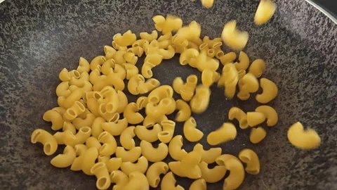 Dry Elbow Macaroni Pasta Falling into a Black Cooking Pot Stock Footage 338342120
