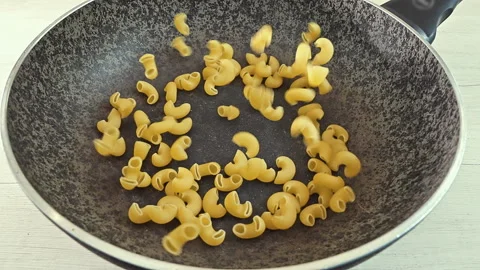 Dry Elbow Macaroni Pasta Falling into a Black Cooking Pot Stock Footage 341439453