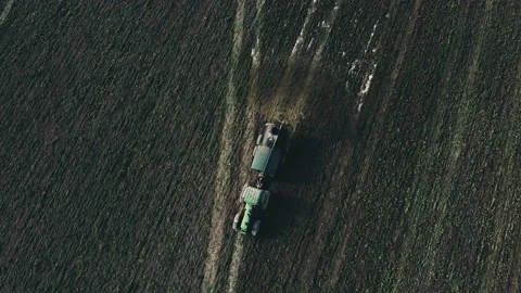 A dry farm field being sprayed by a tractor with a tank of water - slow motio Stock Footage 232452338