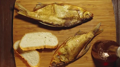 Dry fish beer snack and bread on a table on a chopping board camera zooms in Stock Footage 279230655