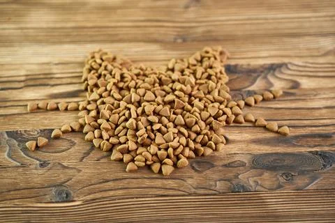 Dry food spread in the shape of a cat's head on a wooden background. Stock Photos
