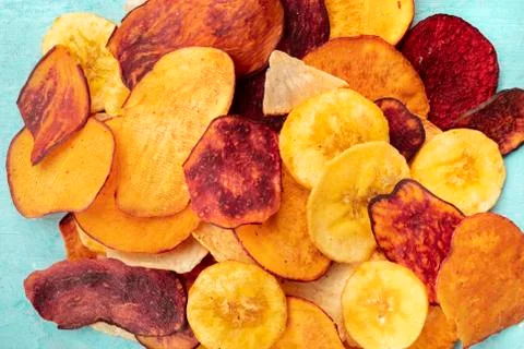 Dry fruit and vegetable chips, healthy vegan snack, a mixed heap on a blue 写真素材