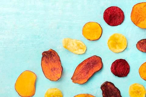 Dry fruit and vegetable chips, overhead shot on a vibrant blue background Stock Photos