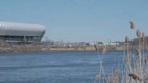 Dry Grass on Riverside with Modern Stadium in Background Video stock 306195972