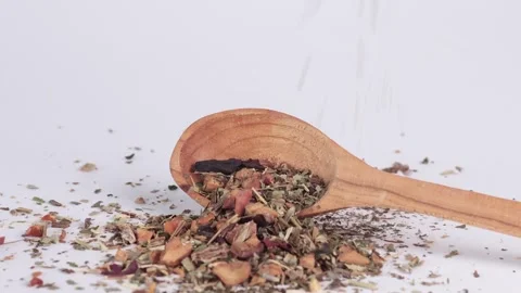 Dry green tea with fruit pieces fall on wooden spoon on white background. Drinks Stock Footage 310870058