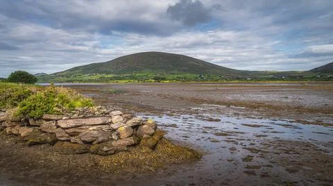Dry marsh after ebb tide with stone pier and mountain in the background in Ri Stock Photos