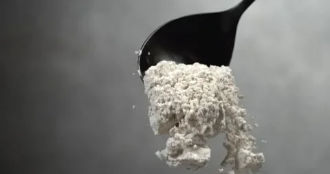 Dry milk powder falling from black spoon in super slow motion Stock Footage 342590964