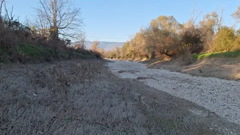 Dry Muddy Riverbed with Pebbles and Mountain Backdrop in an Autumn Sunset Stock Footage 320896895