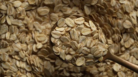 Dry oat flakes in a metal spoon, top view on oat grains background rotates Stock Footage 306090744