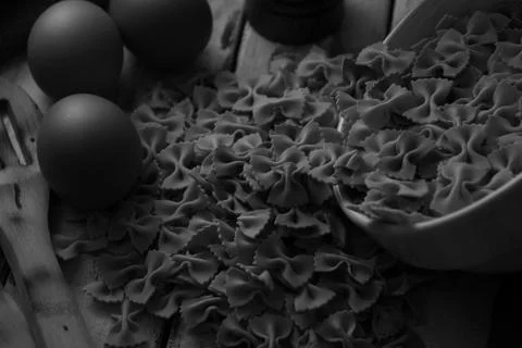 Dry pasta on rustic wood and fresh eggs in black and white Stock Photos